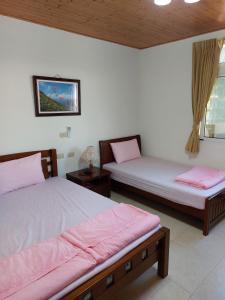 2 Betten in einem Zimmer mit rosa Bettwäsche in der Unterkunft 今友緣二館民宿 in Dongyin/