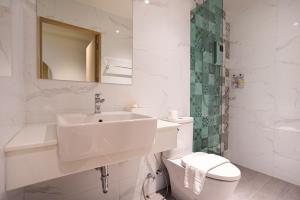 a white bathroom with a sink and a toilet at PS23 Residence in Hat Yai