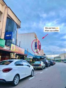 a white car is parked on the side of a street at 暖居Mersing Muji Cottage 0.3km Jeti Mersing Centre in Mersing