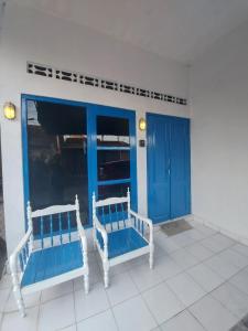 two white benches on a porch with blue doors at FHStay Malioboro in Timuran