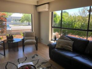 a living room with a couch and a table and windows at Lake Apartment in Wendouree