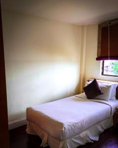 a bedroom with a bed with white sheets and a window at LANGKAWI LAGOON RESORT OCEAN SUITE in Pantai Cenang