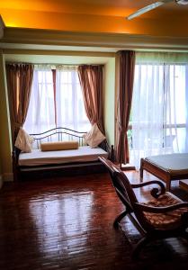 um quarto com uma cama, uma cadeira e janelas em LANGKAWI LAGOON RESORT OCEAN SUITE em Pantai Cenang