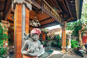 una estatua delante de un edificio con una señal en Bali Summer Hotel by Amerta, en Kuta