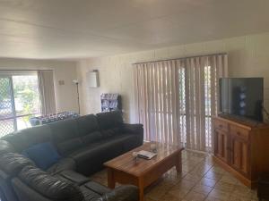 a living room with a couch and a tv at The Red Piranha Rainbow Beach in Rainbow Beach