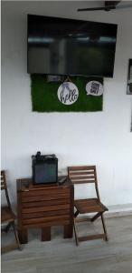 a tv on a wall with two chairs and a table at Cozy Townhouse & Terrace/Pool in La Ceiba
