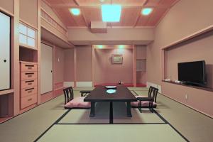 a dining room with a table and chairs and a tv at Kasuga Hotel in Nara