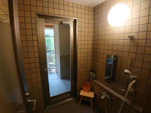 a bathroom with a shower with a toilet and a mirror at Kasuga Hotel in Nara