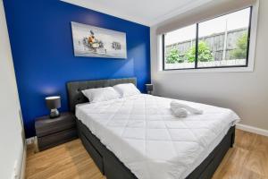 a bedroom with a large bed with a blue wall at Newly Built Guest House Walk to Lake in Toukley