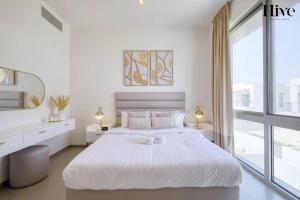 a white bedroom with a large white bed and a window at Ultra Modern 4 Bedroom Villa in Arabian Ranches 2 in Dubai