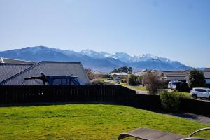 a yard with a fence and mountains in the background at Spacious Family Friendly Parkside in Kaikoura
