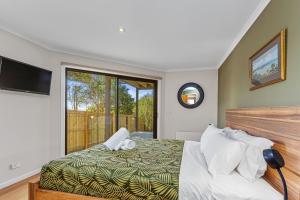 a bedroom with a bed and a large window at Achilles in Apollo Bay