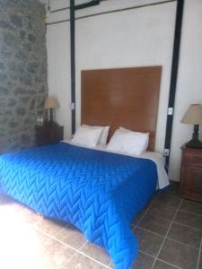 a large bed with a blue comforter in a bedroom at Hotel Vitorina in Atlixco