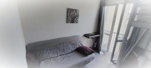 ein Sofa in einem weißen Zimmer mit einem Bild an der Wand in der Unterkunft Cosy confort appart Cognac in Cognac