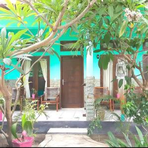 a front door of a house with chairs and trees at Gili pelangi in Gili Trawangan