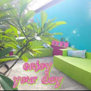 a room with a plant and a sign that says enjoy your day at Gili pelangi in Gili Trawangan