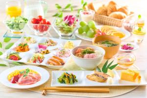 einen Tisch mit Teller mit Lebensmitteln und Schüsseln mit Lebensmitteln in der Unterkunft Ooedo Onsen Monogatari Hotel Shinko in Fuefuki