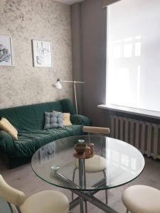 a living room with a glass table and a green couch at Artsy central flat in Rīga
