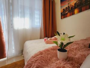 Un dormitorio con una cama con una manta rosa y una planta en Fame Residences Staycation, en Manila