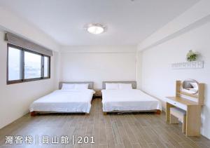 a room with two beds and a desk and a window at Yuanshan Dahu Homestay in Yuanshan