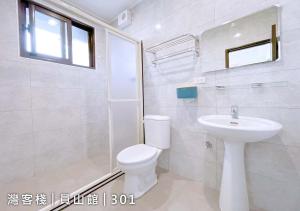 a white bathroom with a toilet and a sink at Yuanshan Dahu Homestay in Yuanshan