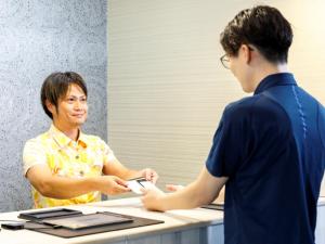 a man is handing another man a cell phone at Miyazaki Lions Hotel in Miyazaki