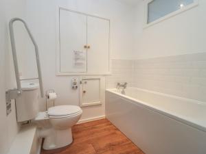 a white bathroom with a toilet and a bath tub at Cotswold View in Cheltenham +26 photos