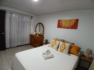 Schlafzimmer mit einem großen weißen Bett und einem Spiegel in der Unterkunft Ledy's Inn in Turrialba