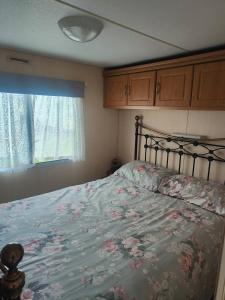 a bedroom with a bed with a floral bedspread and a window at The hobbits in Dymchurch