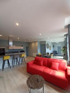 a living room with a red couch and a kitchen at Appartement Le palais autun in Autun