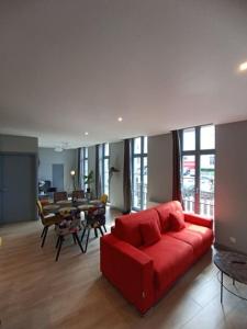 a living room with a red couch and a table at Appartement Le palais autun in Autun