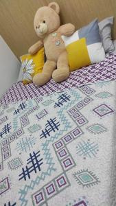 un ours en peluche assis au-dessus d'un lit dans l'établissement City View 19th floor Fern at Grass Residences, à Manille