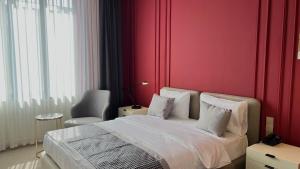 a bedroom with red walls and a bed and a chair at Bentley Hotel Tashkent in Tashkent