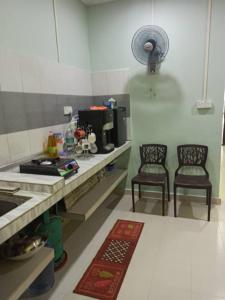 een keuken met 2 stoelen en een aanrecht met een wastafel bij Homestay FarHaA in Tanah Merah