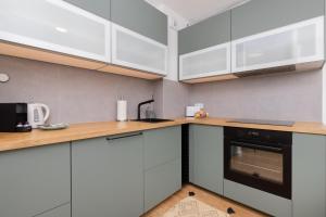 a kitchen with white cabinets and wooden counter tops at Bright & Trendy Gdańsk Apartment with Balcony by Renters in Gdańsk