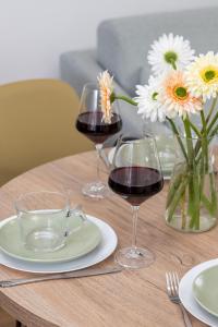 three glasses of wine on a wooden table with flowers at Bright & Trendy Gdańsk Apartment with Balcony by Renters in Gdańsk