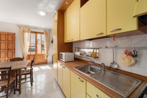 eine Küche mit gelben Schränken, einer Spüle und einem Tisch in der Unterkunft San Pietro's House in Villa San Pietro