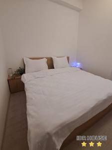 1 dormitorio con 1 cama grande con sábanas y almohadas blancas en IDR HOUSE, en Buzău