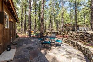a patio with a table and chairs in the woods at Autumn Mountain Vacations - Book Now! Rogue Bear Cabin in Williams