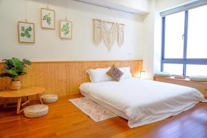 a bedroom with a large white bed and a table at Pottery Flower B&B in Jiji