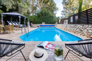 a swimming pool with two chairs and a table with a hat at THE HOUSE ROSH PINA - 2BRM WITH POOl in Rosh Pinna