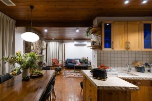 cocina con armarios de madera y sala de estar. en THE HOUSE ROSH PINA - 2BRM WITH POOl, en Rosh Pina