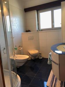 ein Badezimmer mit 2 WCs, einem Waschbecken und einer Dusche in der Unterkunft Ferienwohnung mit wunderschöne Aussicht, Whirlpool und Sauna in Gordola
