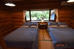 grupa łóżek w pokoju z oknem w obiekcie Pension Prussian Blue w mieście Miyako-jima
