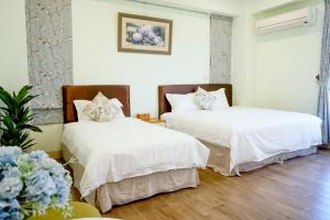 two beds in a room with white sheets and flowers at Pottery Flower B&B in Jiji