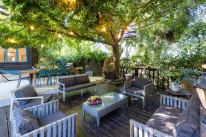a patio with chairs and tables under a tree at THE HOUSE ROSH PINA - 3BRM WITH POOl in Rosh Pinna