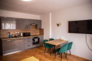 une cuisine avec une table en bois et des chaises vertes dans l'établissement Prostorný byt v centru u řeky, 2 ložnice, balkón, à Hradec Králové