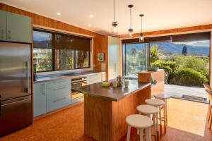cocina con ventana grande y barra con taburetes en Bach 7 by The Sea - Marahau Holiday Home, en Marahau