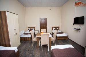 a room with a table and chairs and two beds at Grand Qafqaz Hostel in Ganja