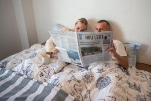 a man and woman laying in bed reading a newspaper at Merevaatega majutus Kärdla sadamas in Kärdla